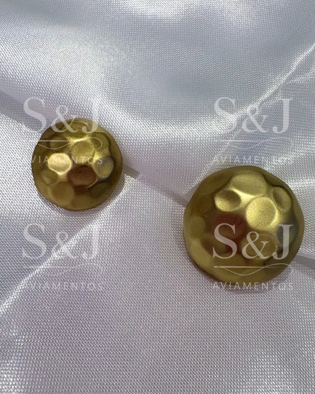 Botão metálico dourado com textura martelada e acabamento fosco