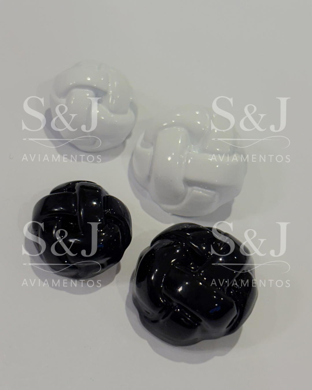 Botão trançado com acabamento brilhoso, disponível em preto e branco. Clássico, moderno e versátil.